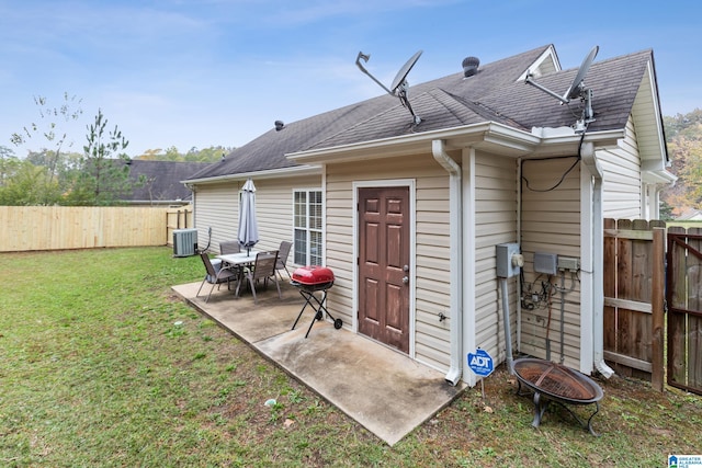 rear view of house with a patio area, a yard, central AC unit, and an outdoor fire pit