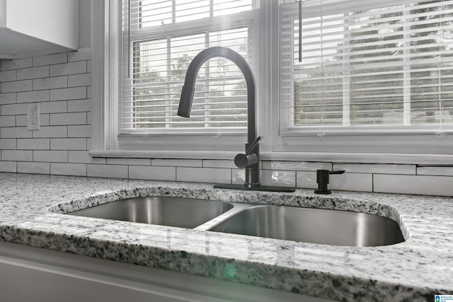 interior details with light stone counters, sink, and tasteful backsplash