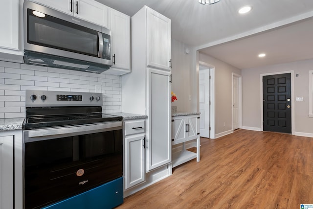 kitchen featuring decorative backsplash, appliances with stainless steel finishes, light stone counters, light hardwood / wood-style flooring, and white cabinets