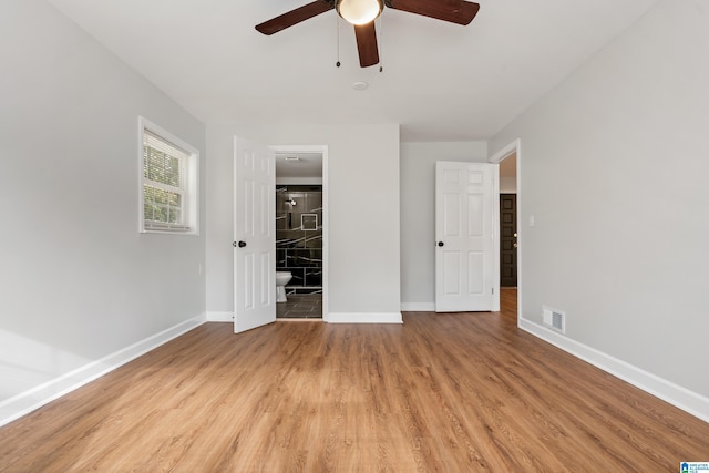 unfurnished bedroom featuring ceiling fan, ensuite bathroom, and light wood-type flooring