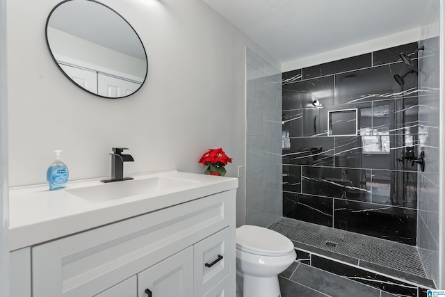 bathroom with tile patterned flooring, toilet, vanity, and tiled shower