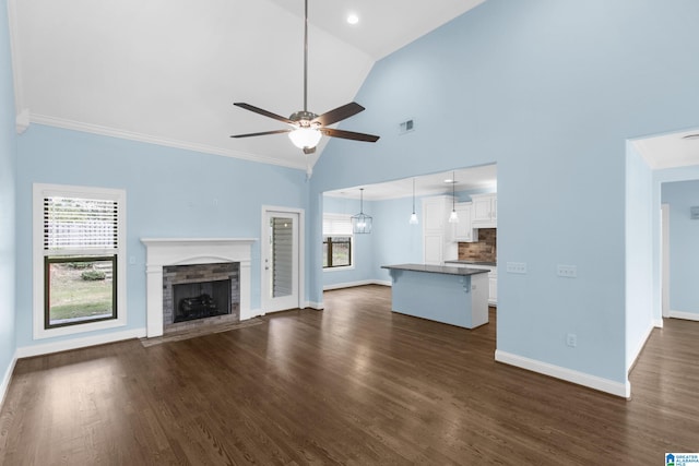 unfurnished living room with high vaulted ceiling, ceiling fan, dark wood-type flooring, and crown molding