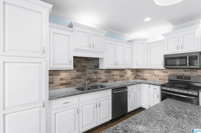 kitchen with dark stone countertops, white cabinetry, sink, and stainless steel appliances