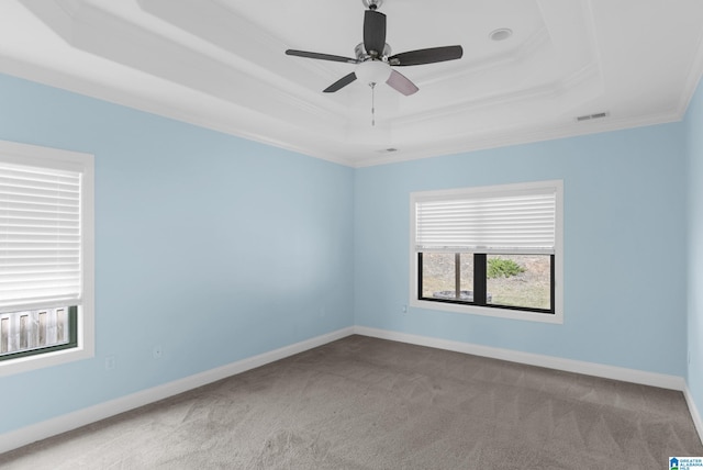 carpeted empty room with a tray ceiling, ceiling fan, and ornamental molding