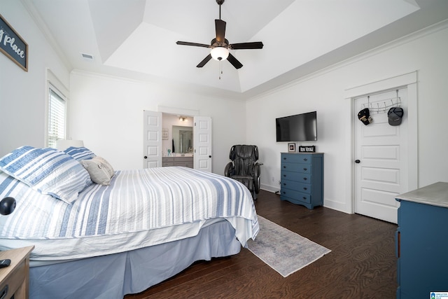 bedroom featuring ceiling fan, ornamental molding, connected bathroom, a tray ceiling, and dark hardwood / wood-style flooring