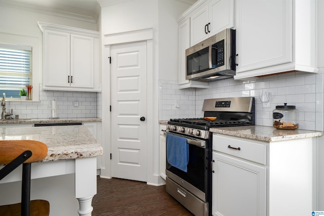 kitchen with backsplash, light stone countertops, appliances with stainless steel finishes, dark hardwood / wood-style flooring, and white cabinetry