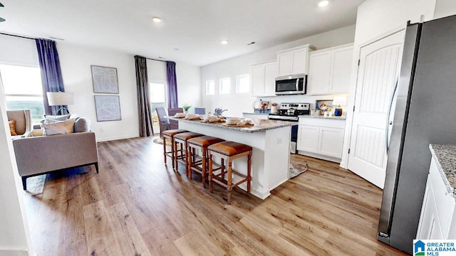 kitchen with white cabinets, plenty of natural light, a kitchen island, and appliances with stainless steel finishes