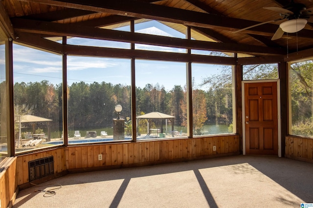 unfurnished sunroom featuring vaulted ceiling with beams, a wealth of natural light, ceiling fan, and wooden ceiling