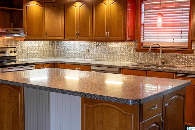 kitchen with decorative backsplash, stainless steel appliances, a kitchen island, and sink