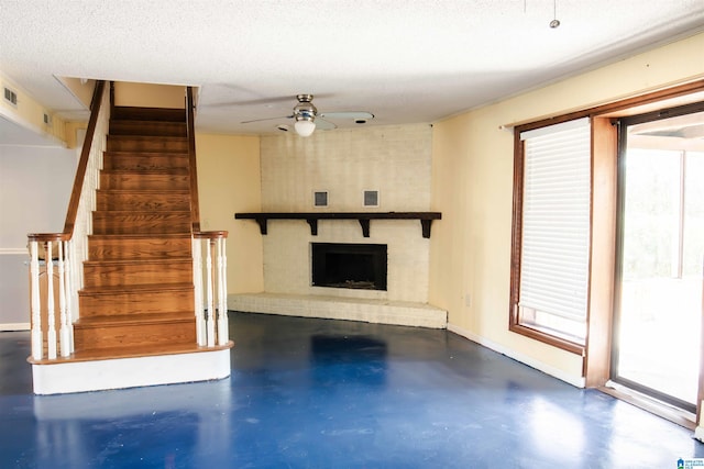 unfurnished living room with a fireplace, ceiling fan, and a textured ceiling