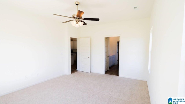 unfurnished bedroom with connected bathroom, light colored carpet, and ceiling fan