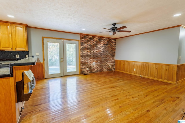 unfurnished living room with ceiling fan, light hardwood / wood-style floors, crown molding, and a textured ceiling