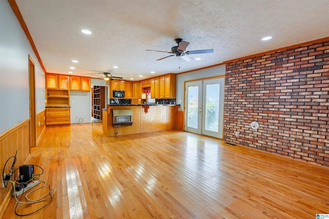 unfurnished living room featuring a textured ceiling, crown molding, light hardwood / wood-style flooring, and french doors