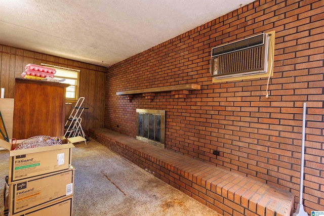 carpeted living room featuring wood walls, a textured ceiling, brick wall, and a brick fireplace