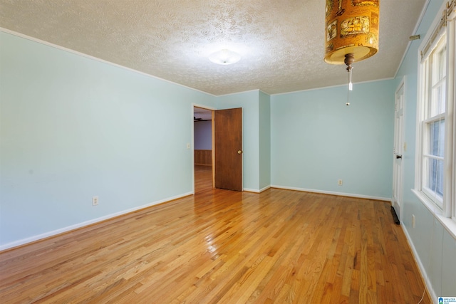 empty room with crown molding, a textured ceiling, and light hardwood / wood-style flooring