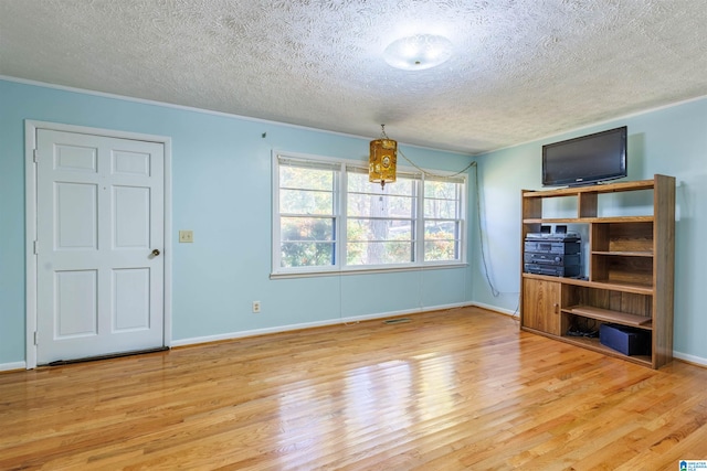 unfurnished living room with light hardwood / wood-style floors, a textured ceiling, and ornamental molding