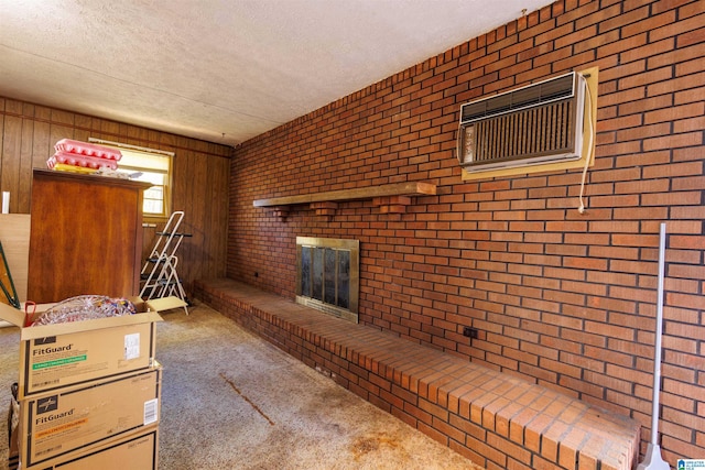 694 Center Point Rd, Sylacauga, AL 35151 - unfurnished living room with a fireplace, a textured ceiling, brick wall, carpet floors, and a wall unit AC