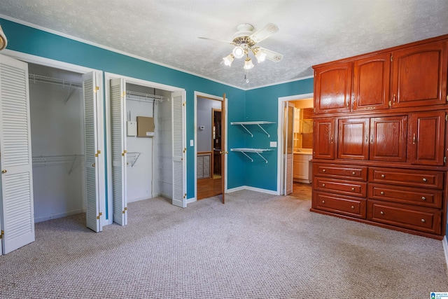 unfurnished bedroom featuring light carpet, connected bathroom, two closets, and ceiling fan