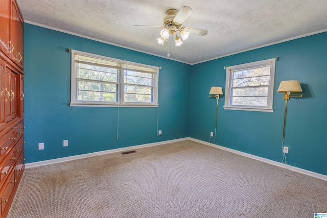 carpeted empty room featuring ceiling fan, a textured ceiling, and ornamental molding