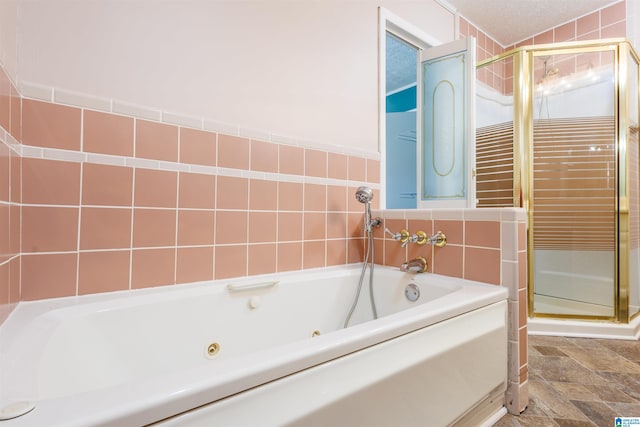 bathroom with a textured ceiling, tile walls, and independent shower and bath