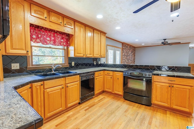 kitchen with tasteful backsplash, sink, black appliances, and light hardwood / wood-style floors