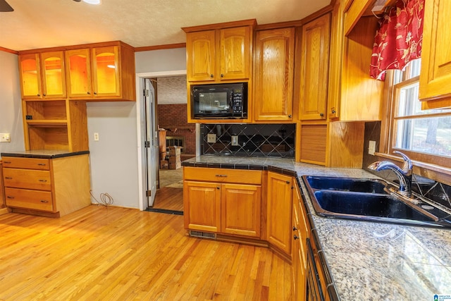 kitchen with backsplash, sink, light hardwood / wood-style flooring, ornamental molding, and dishwashing machine