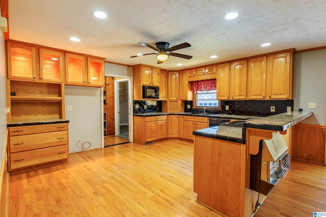 kitchen featuring kitchen peninsula, black microwave, light hardwood / wood-style flooring, and sink