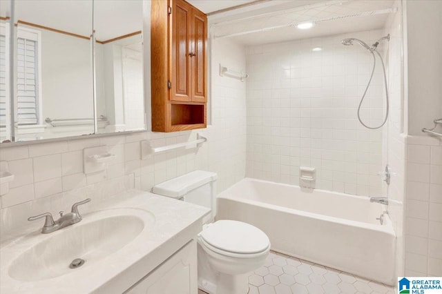 full bathroom featuring tile patterned floors, toilet, vanity, tile walls, and tiled shower / bath