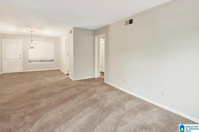 unfurnished room featuring a notable chandelier and light carpet