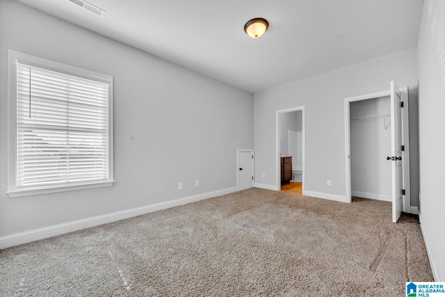 unfurnished bedroom featuring ensuite bathroom and light carpet