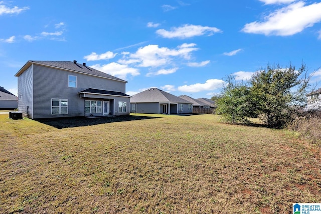 rear view of property with a yard and central AC