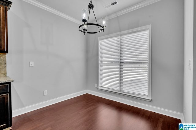 unfurnished dining area featuring dark hardwood / wood-style flooring, an inviting chandelier, and crown molding