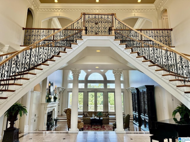 foyer entrance featuring french doors, a towering ceiling, decorative columns, and crown molding