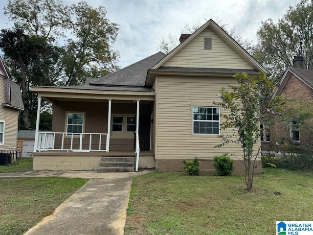 bungalow featuring cooling unit, covered porch, and a front yard