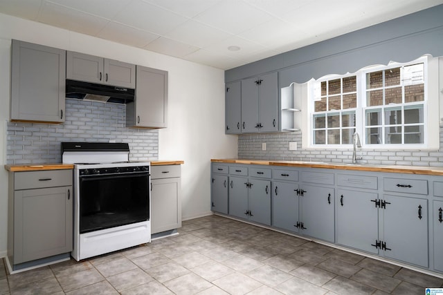 kitchen with butcher block countertops, sink, gray cabinetry, and white stove