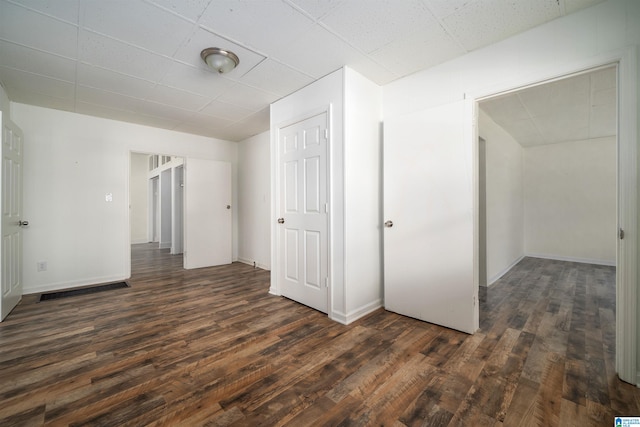 unfurnished bedroom with dark hardwood / wood-style floors and a drop ceiling