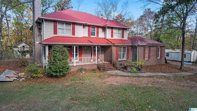 view of front of home featuring a storage unit, covered porch, and a front lawn