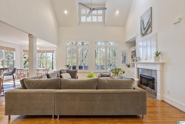 living room with a premium fireplace, high vaulted ceiling, light hardwood / wood-style floors, and ceiling fan