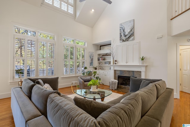 living room with a tile fireplace, a wealth of natural light, high vaulted ceiling, and light wood-type flooring