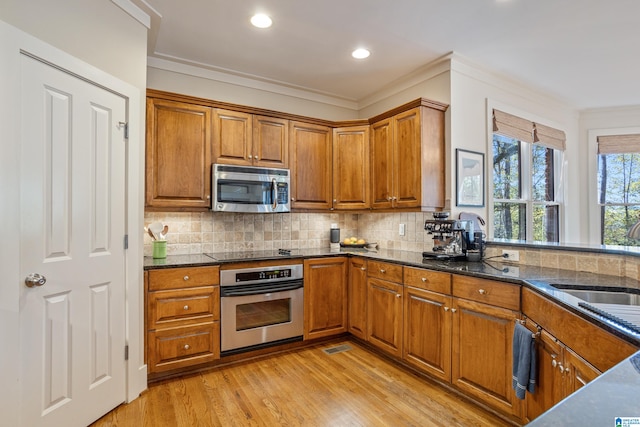 kitchen with crown molding, sink, stainless steel appliances, and light hardwood / wood-style flooring