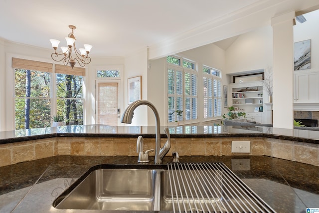 kitchen with a notable chandelier, dark stone countertops, sink, and crown molding