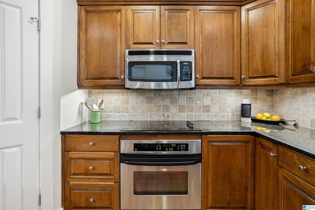 kitchen with decorative backsplash, appliances with stainless steel finishes, and dark stone counters