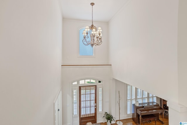 foyer entrance with hardwood / wood-style flooring, crown molding, and an inviting chandelier