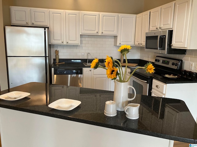 kitchen featuring white cabinets, appliances with stainless steel finishes, tasteful backsplash, and dark stone countertops