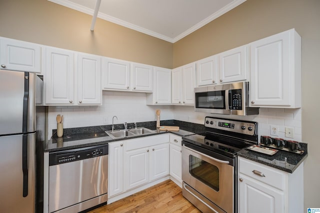 kitchen featuring white cabinetry, sink, stainless steel appliances, dark stone countertops, and light hardwood / wood-style floors