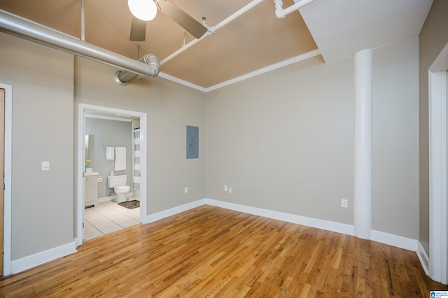 spare room with light wood-type flooring, electric panel, ceiling fan, and crown molding