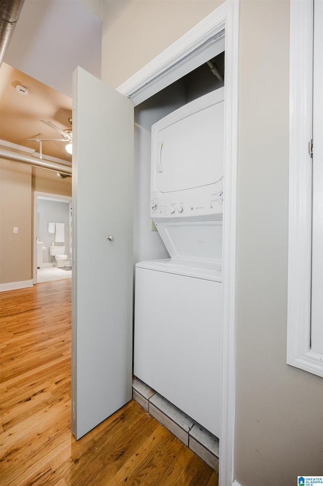 laundry room featuring hardwood / wood-style flooring, ceiling fan, and stacked washer and clothes dryer