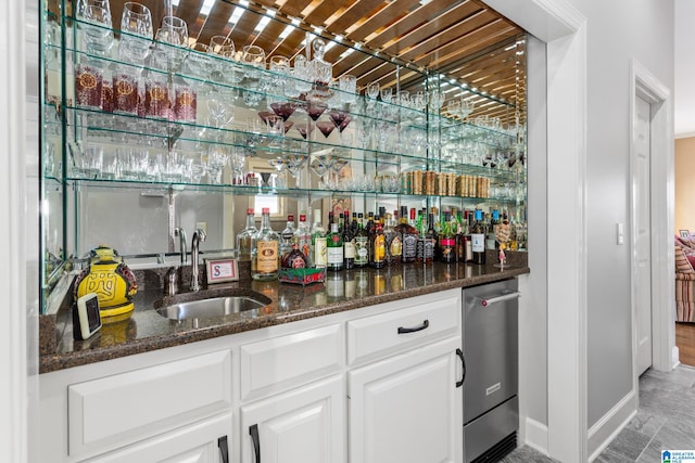 bar with sink, hardwood / wood-style flooring, dark stone countertops, dishwasher, and white cabinetry