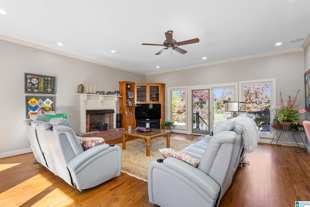 living room featuring a fireplace, ceiling fan, crown molding, and light hardwood / wood-style flooring