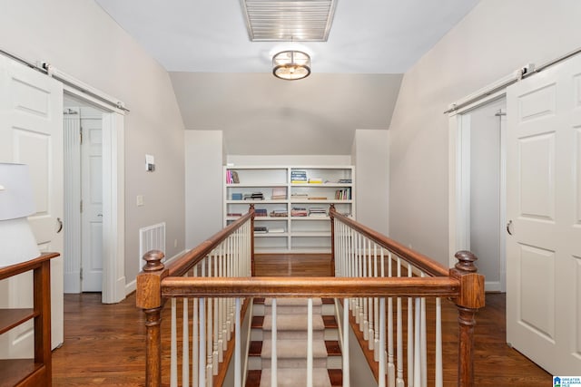 staircase featuring hardwood / wood-style flooring, a barn door, and lofted ceiling